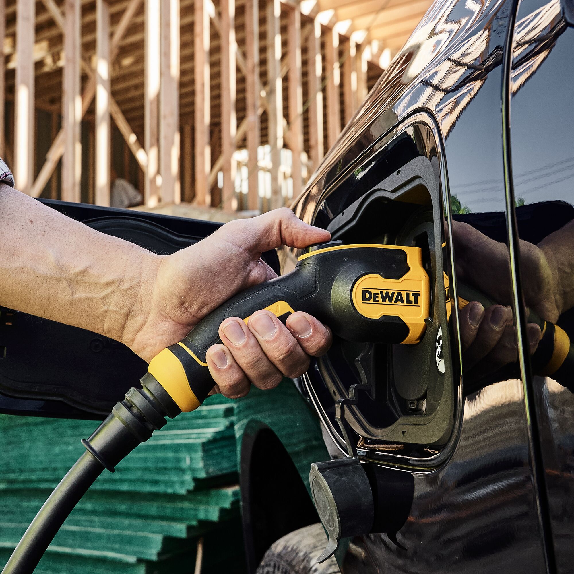HAND HOLDING THE INSERTED ELECTRIC VEHICLE CHARGING GUN INTO PICKUP TRUCK
